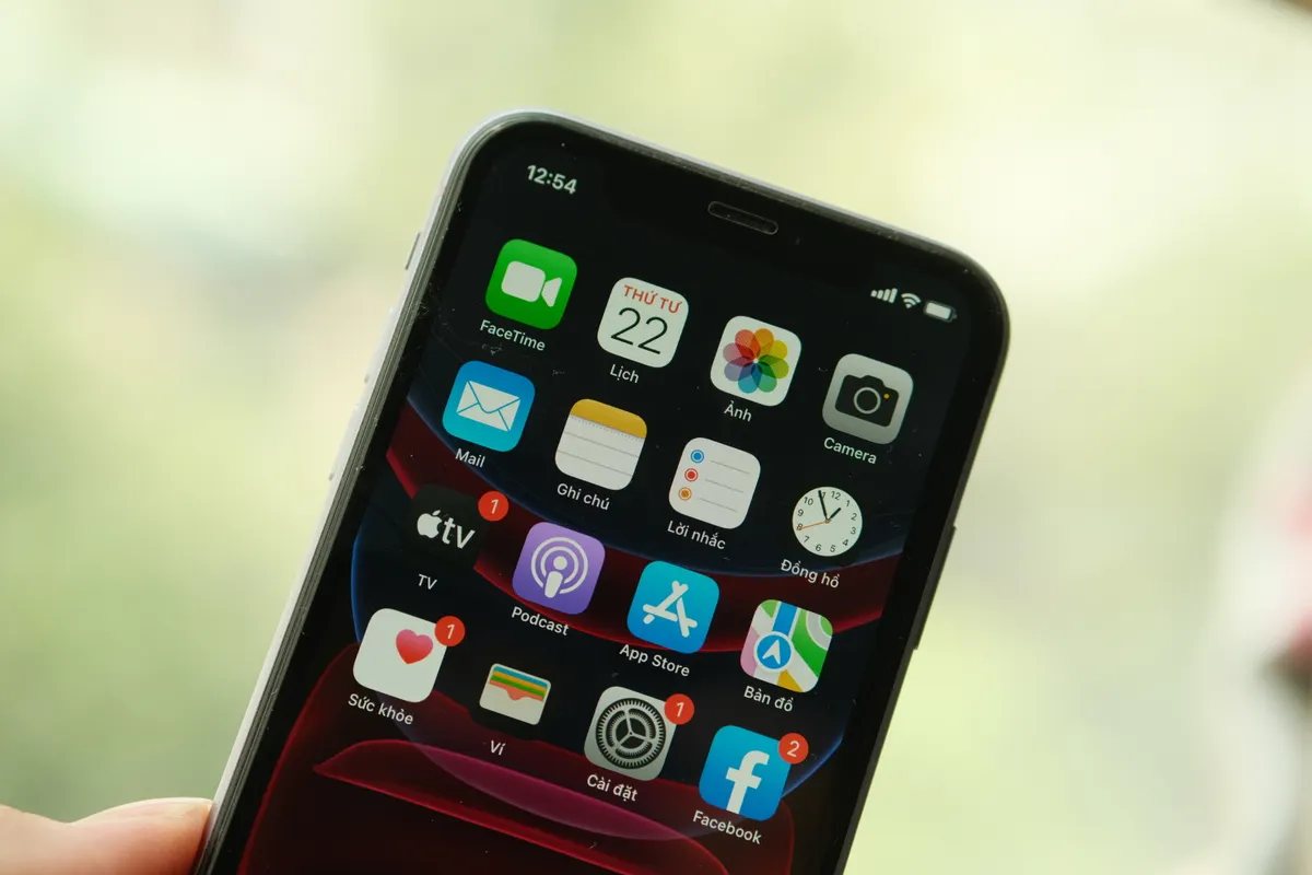 Bàn tay cầm iPhone với các biểu tượng ứng dụng rõ trên màn hình